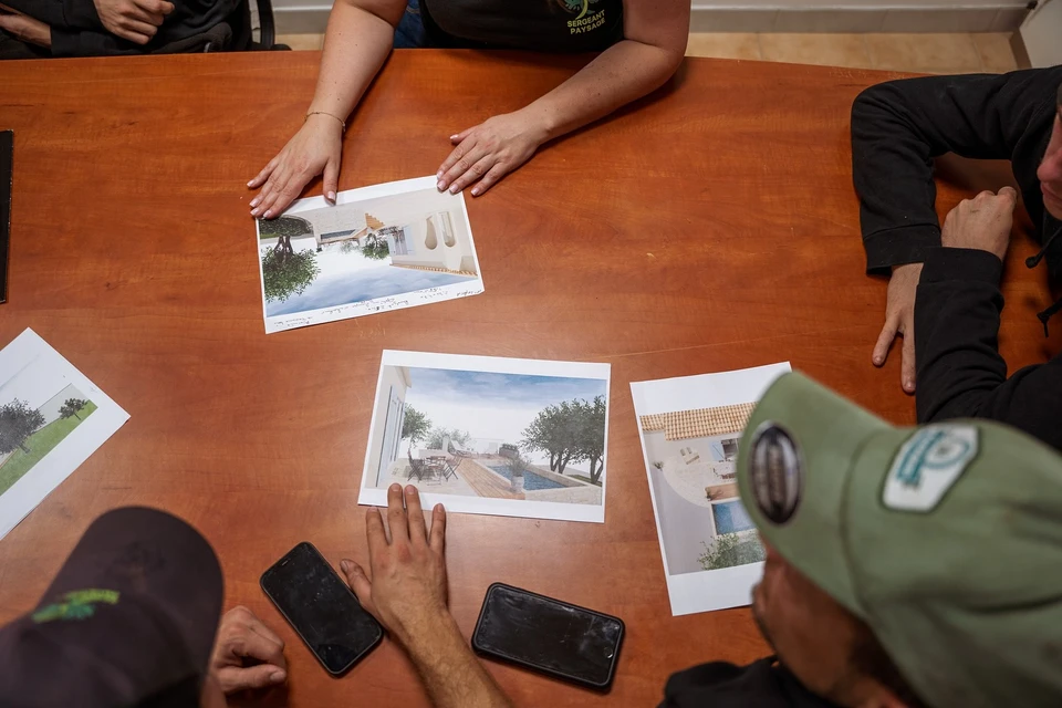 Plantation d'un jeune arbre en extérieur par une personne agenouillée portant des gants de jardinage blancs