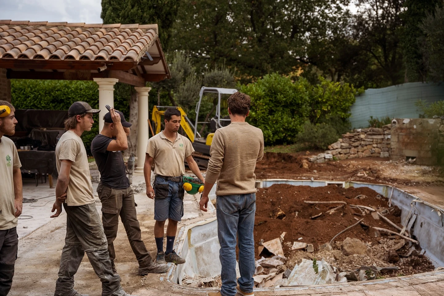 Groupe de neuf personnes enlacées face à un paysage lacustre au coucher du soleil, bras levés en signe de célébration et unité