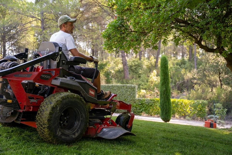 Jardin paysager avec terrasse en bois surélevée, mobilier de jardin en fer forgé noir et coussins beiges
