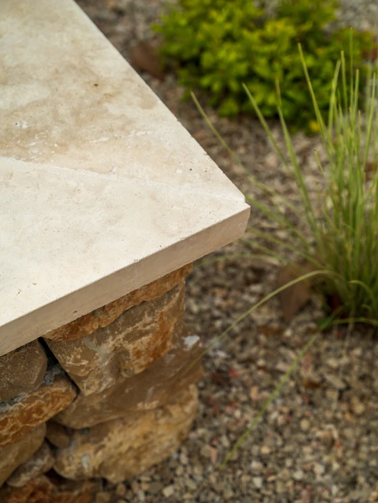 Jardin extérieur avec muret en pierres sèches de différentes tailles et couleurs, certaines couvertes de mousse