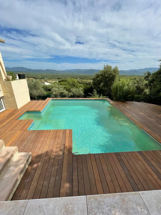 Terrasse extérieure moderne avec platelage en bois composite, pelouse synthétique verte et grande jardinière carrée en béton blanc contenant un yucca rostrata aux feuilles linéaires vert-jaune aux pointes orangées